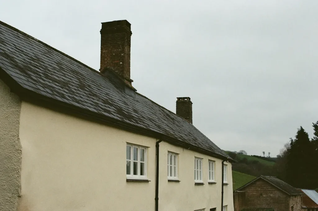 Maison aux murs clairs avec toiture en ardoise et cheminées